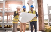 People standing within a construction site reviewing a site drawing
