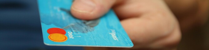 Person presenting a blue payment card to the viewer
