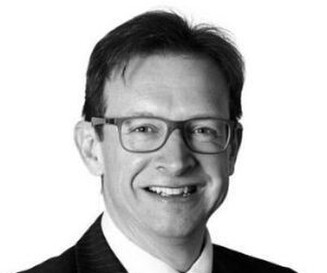 Headshot of Wollens solicitor, Simon Bean, in black & white with him smiling at the camera