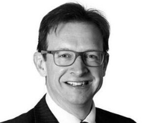 Headshot of Wollens solicitor, Simon Bean, in black & white with him smiling at the camera