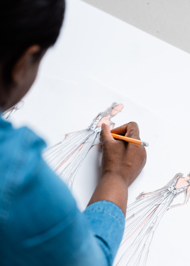 Bridal fashion designer Kate Edmondson, sketching bespoke wedding dress designs during a bridal consultation