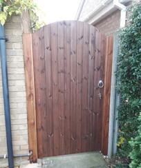 Tongue and grooved clad gate with curved top.