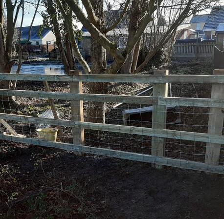 Post and rail fencing with stock netting attacjhed.