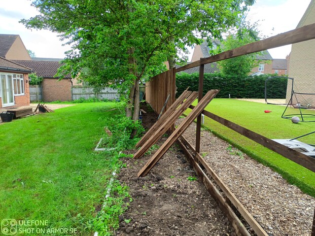 Image shows the construction of closeboard fencing on Durapost classic posts. At this point the posts are all in, the rails and gravelboards are fitted and cladding with the feather edge has commenced.