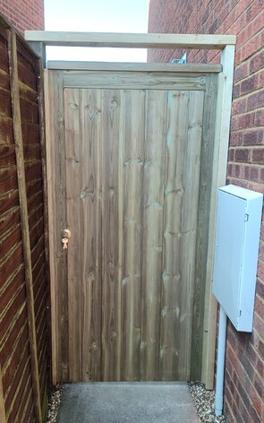This is a fully framed, ledged and braced gate clad with tongue and grooved timber and treated in green Tanalith wood treatment.  It is fitted to timber wall plates and has a top bar fitted to keep the closing gate post stable.  Fitted with a deadlock.