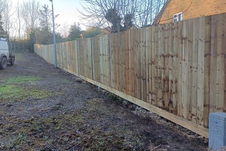 A run of timber closeboard fencing installed using recessed concrete posts and cant rails.