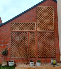 Image shows diamond lattice trellis panels fitted to the side of a garage wall.
