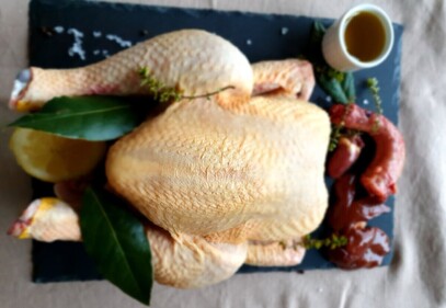 Redwoods Farm pasture raised soy free whole chicken placed on a slate board with giblets, herbs, lemon and oil garnish