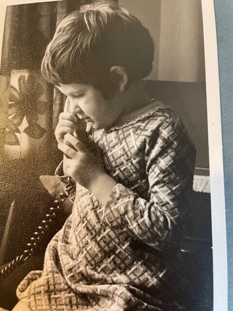 A back and white old photograph of a young girl on the phone. Style of dress and the phone is from the 1960s